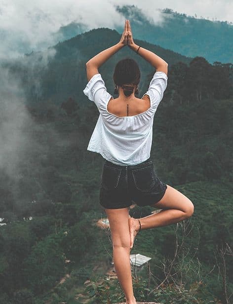 Woman in a tree pose on a mountain trail