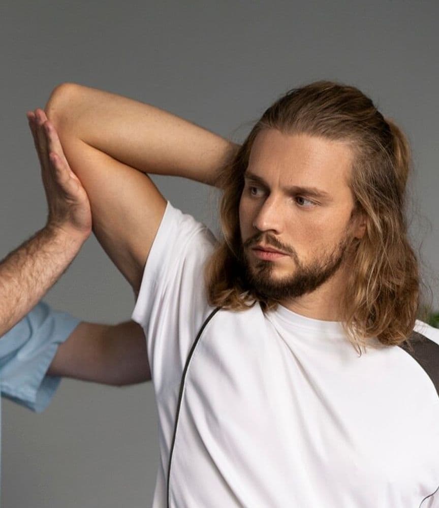 Therapist guiding a man's shoulder stretch